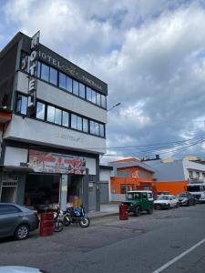 a building with cars parked in a parking lot at Hotel Tonchala Centro in Armenia