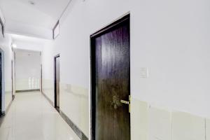 HasanganjHotel O SRV Palace的走廊里有一扇黑色的门，墙壁是白色的