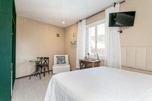 Un dormitorio con una cama, una silla y una mesa. en Guesthouse, en Florianópolis