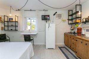 Una cocina con un refrigerador y una mesa dentro. en Guesthouse, en Florianópolis