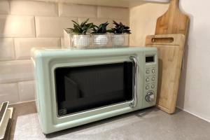 a microwave with three plants on top of it at Warm & Cosy 1-Bed Apartment in Hatfield in Hatfield +22 photos