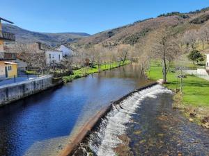 a river with a waterfall in a city at Casa Dos Avós - Alojamento Local in Bragança