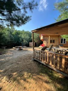 a cabin with a deck and chairs in the yard at Forest Bunkie Trails & Stargazing in Simcoe
