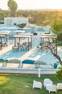 a patio with tables and chairs and tables and chairs at Boomerang Village 4 Stars in Torre Colimena