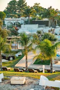 a park with palm trees and benches and a building at Boomerang Village 4 Stars in Torre Colimena
