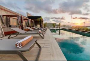 a row of lounge chairs next to a swimming pool at New! Modern Escape, Tuk Tierra In Tulum in Tulum