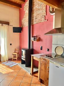 a kitchen with a stove and a red wall at El Aravalle, Altillo del Aravalle in Umbrías