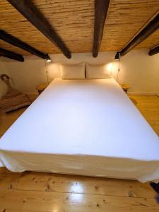 Cette chambre comprend un grand lit blanc et du parquet. dans l'établissement Laranjeira 2 by AlmaAlgarvia, à Santa Bárbara de Nexe