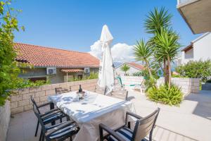 a table with chairs and an umbrella on a patio at Apartments Veve in Postira