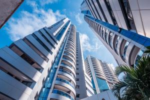 a view of a tall building with palm trees at Apto 19º andar, piscina, academia, garagem, ao lado do Shopping Salvador in Salvador