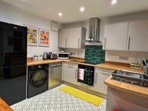 a kitchen with white cabinets and a washer and dryer at Darfield House Barnsley in Barnsley