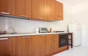 a kitchen with wooden cabinets and a white refrigerator at Stunning Apartment In Agropoli in Agropoli