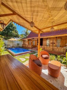 a patio with a table and chairs and a pool at Dunya Villa in Gili Air