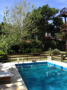 een zwembad in een tuin met een hek bij Hola! in Valeria del Mar