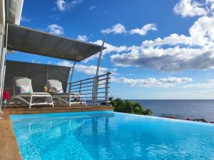 a swimming pool with two chairs and the ocean at Blue Haven Villa 1 in Bouillante