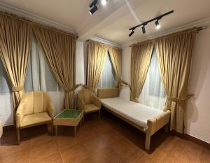 a bedroom with a bed and two chairs and windows at Bhurban Suites in Murree +23 photos