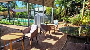 a patio with chairs and a table and a fence at Rainforest Motel, Mission Beach in Mission Beach