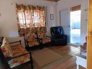 a living room with a couch and a chair and a window at Casa de Campo Refúgio Jaguary in Monte Verde