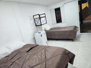 a room with two beds and a small refrigerator at Pousada Flor do Caribe in Rio das Ostras +42 photos