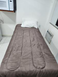 a bed with a brown comforter in a room at Pousada Flor do Caribe in Rio das Ostras