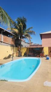 a large blue swimming pool next to a building with a palm tree at Pousada Flor do Caribe in Rio das Ostras