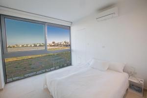 ein Schlafzimmer mit einem weißen Bett und einem großen Fenster in der Unterkunft Villa Limni Enas - Luxury And Contemporary 3 Bedroom Kapparis Villa With Sea View in Paralimni