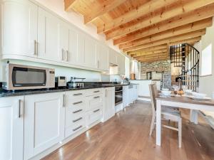cocina con armarios blancos y techo de madera en Tan Y Castell Cottage - Llanmill, en Lampeter-Velfrey 15 fotos más