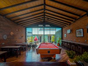 a pool table in a room with tables and chairs at Kuta Cube Hostel in Kuta