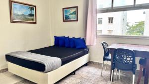 une petite chambre avec un lit et une table dans l'établissement Studio 308 nas Pitangueiras - na quadra da praia!, à Guarujá