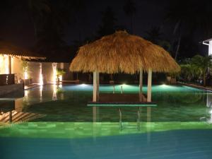 a pool with a straw umbrella and a swimming pool at Handagedara Resort & Spa in Mirissa