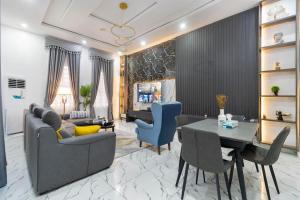 Una sala de estar con un sofá, una mesa y sillas. en Excel 4bedroom orchid lekki Lagos, en Mama