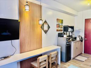 a kitchen with a counter with chairs and a refrigerator at Mesavirre Garden Residences - Cozy Den in Bacolod
