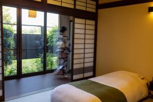 东伊豆町瑞光園-大川 Zuiko Retreat的一个人走进一间有床和窗户的房间