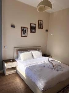 a bedroom with a white bed with two night stands and three pictures at Zeina's apartment in down town in Cairo