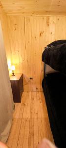 a wooden room with a bed and a night stand at Cabaña La Ranita in Vilches