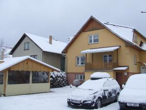 due auto parcheggiate di fronte a una casa ricoperta di neve di Apartmány Grobarčík a Zuberec