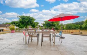 a table and chairs with a red umbrella on a patio at Charmante Maison À La Campagne in Saint-Martial-de-Valette