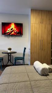 a bedroom with a bed and a table with a fire painting on the wall at Lovely studio apartment in Cochabamba
