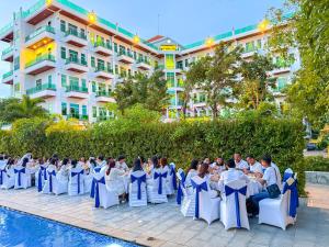 白马市Sangkahak Mith Hotel的一群人坐在泳池边餐桌的椅子上