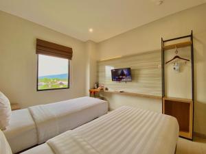 een hotelkamer met twee bedden en een raam bij Front One Hotel Gombong in Gombong