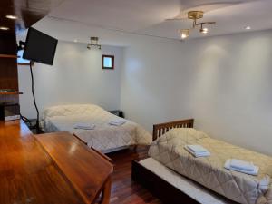 a room with two beds and a table and a tv at Paseo de la Fe in Salta