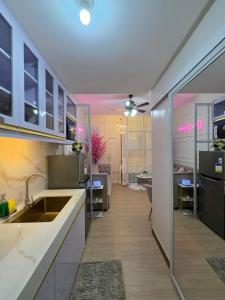 a kitchen with a sink and a living room at Affordable New Staycation Condo in Quezon City in Manila