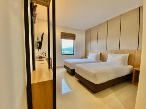 een hotelkamer met twee bedden en een raam bij Front One Hotel Gombong in Gombong