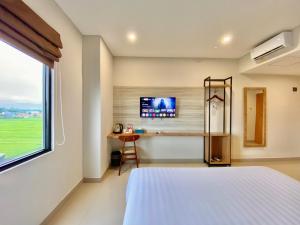 een slaapkamer met een bed en een tv aan de muur bij Front One Hotel Gombong in Gombong