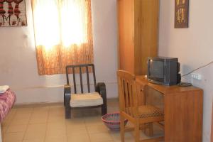 Zimmer mit einem Schreibtisch, einem TV und einem Stuhl in der Unterkunft Hotel de la Liberte in Ouagadougou