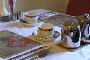 una mesa con dos tazas y platillos y cucharas de plata en The Winchester, en Great Yarmouth