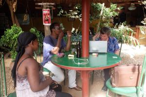 um grupo de pessoas sentadas em torno de uma mesa com um laptop em Hotel de la Liberte em Ouagadougou