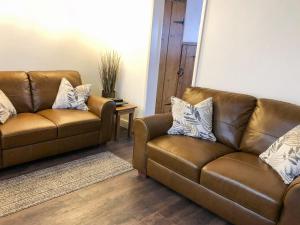 un soggiorno con 2 divani in pelle marrone e un tavolo di Beachview Cottage Scratby a Scratby