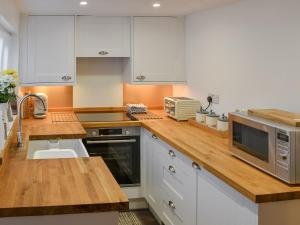 una cucina con mobili bianchi e un piano di lavoro in legno di Beachview Cottage Scratby a Scratby