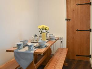 un tavolo con tazze e un vaso con fiori sopra di Beachview Cottage Scratby a Scratby